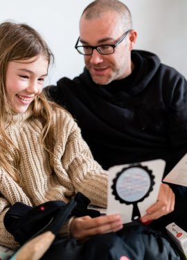 man and young girl examining hey girls education cards