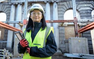 employee of belfour beatty with a construction site in the background